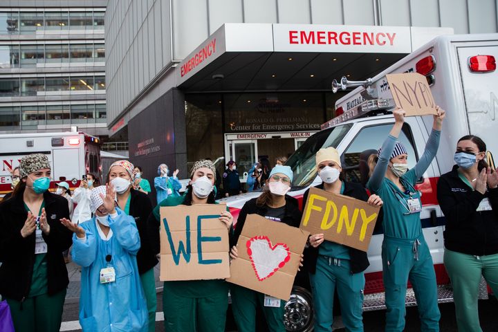 NEW YORK, NY - APRIL 21: Medical workers hold signs outside NYU Langone Health hospital as people applaud to show their appreciation to medical staff and essential workers on the front lines of the coronavirus pandemic on April 21, 2020 in New York City. COVID-19 statistics continue to trend downward in the tri-state region, but New York City has surpassed 132,000 cases since the outbreak. (Photo by Jeenah Moon/Getty Images)
