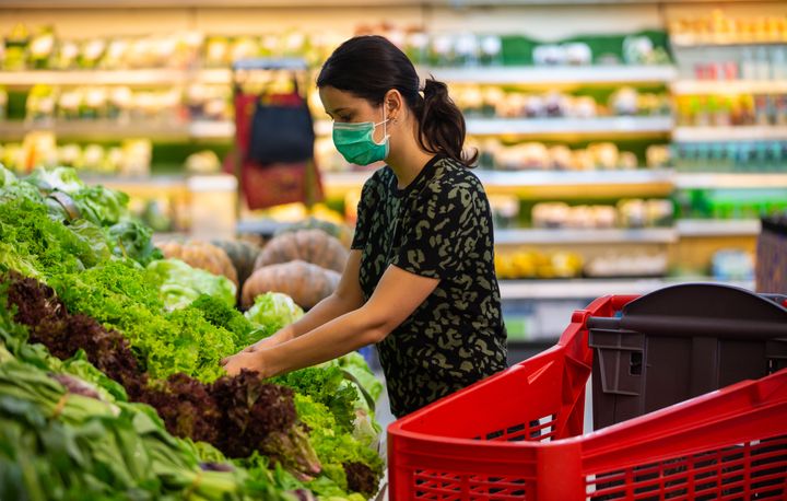 In this stock photo, a woman handles produce at a supermarket. Falling prices for some items gave Canada's struggling consumers a bit of a break in March.