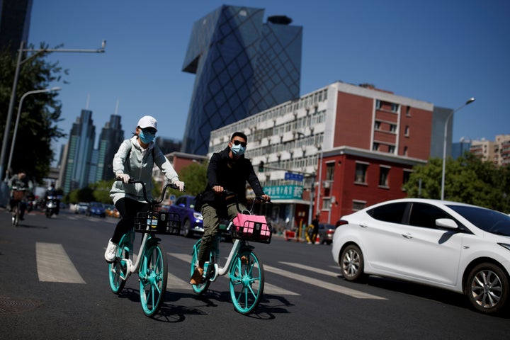 People wear face masks while riding bicycles in Beijing on Tuesday. Air quality has improved in China since the coronavirus outbreak.
