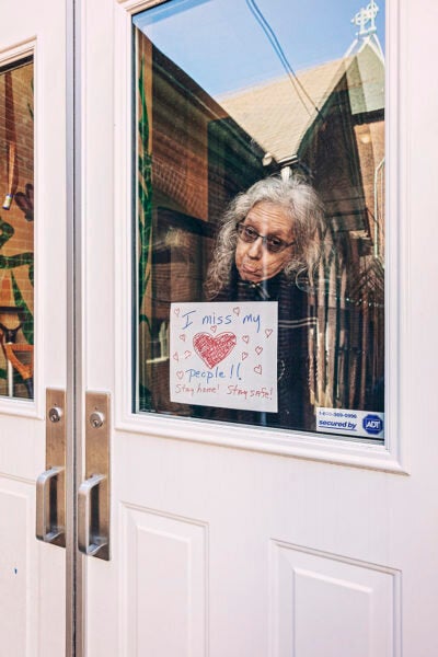 One of Gruenwald's subjects holds up a sign that says "I miss my people!! Stay home! Stay safe!" 