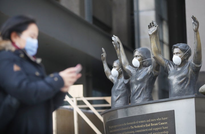 A pedestrian passes statues outside Princess Margaret Hospital in Toronto during the COVID-19 pandemic.