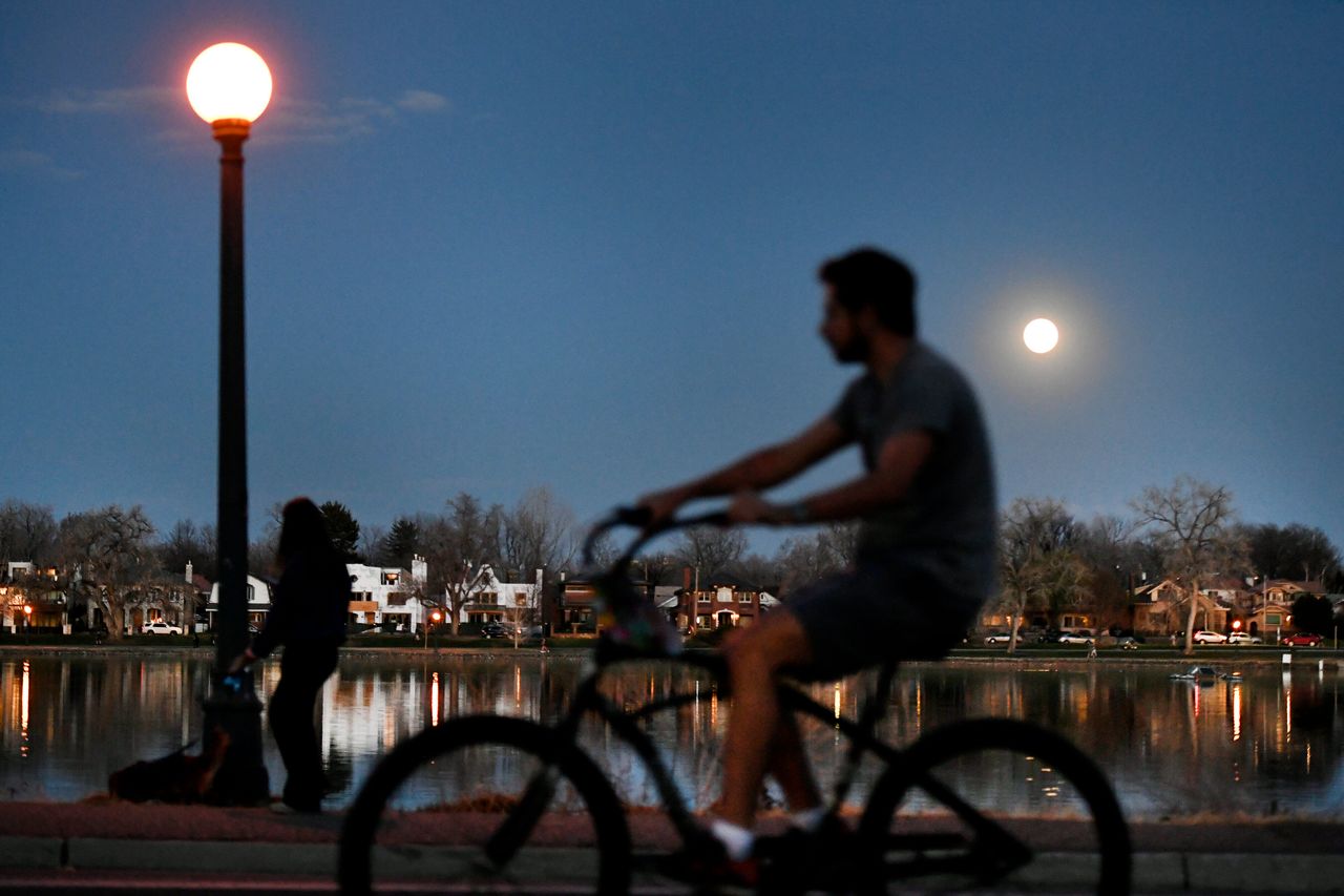 Cyclists and pedestrians pass by Smith Lake in Washington Park on April 7, 2020, in Denver. The city is closing some streets to cars in response to the coronavirus.
