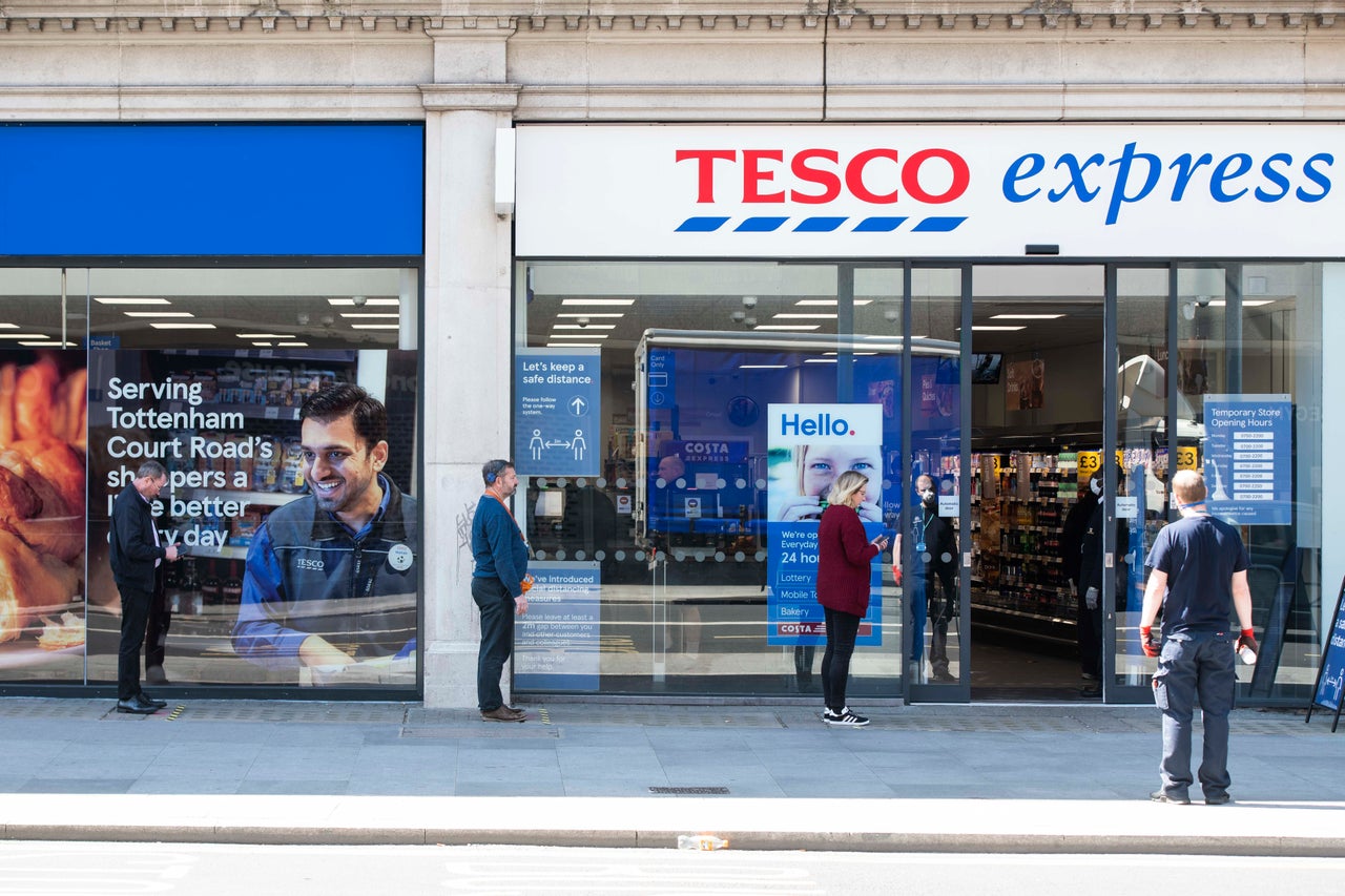 Customers queuing two metres apart outside the Tesco Express store on Tottenham Court Road, London