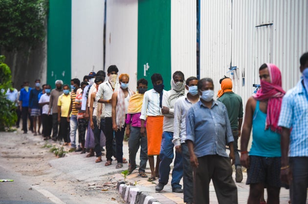 NEW DELHI, INDIA - APRIL 14: Stranded migrant workers and homeless people queue to collect food at Safdarjung...