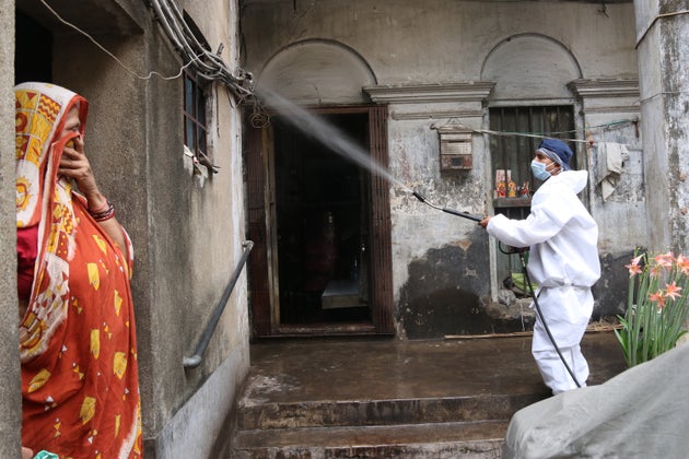 A municipal corporation worker sprays disinfectant at a home in North Kolkata after the area was sealed...
