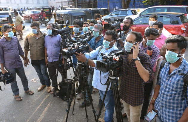 Journalists wearing surgical masks stand outside a government general hospital in Thrissur, Jan. 30,