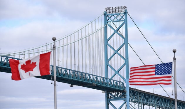 Canadian and American flags fly near the Ambassador Bridge at the Canada-USA border crossing in Windsor, Ont. on March 21, 2020. 