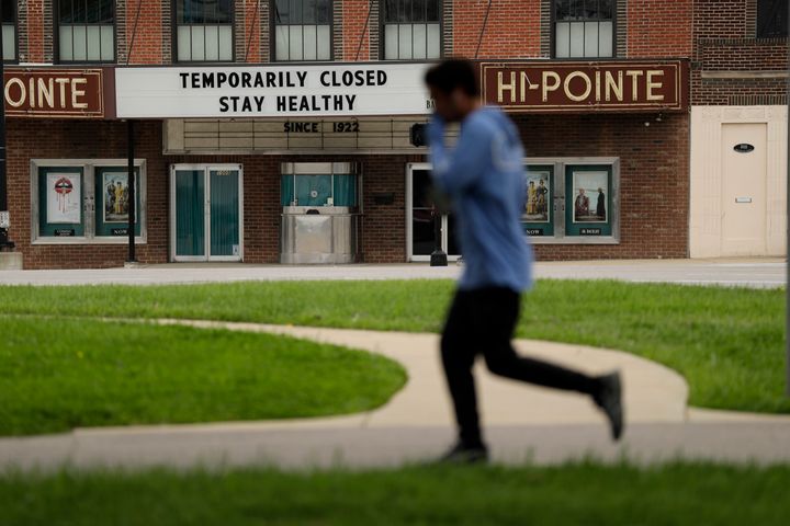 A person jogs past a movie theater temporarily closed due to the coronavirus outbreak on April 6 in St. Louis.