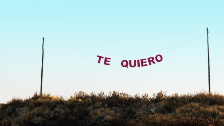 Words "te quiero" hung between two poles with a rope, in a blue sky. Concept of love.