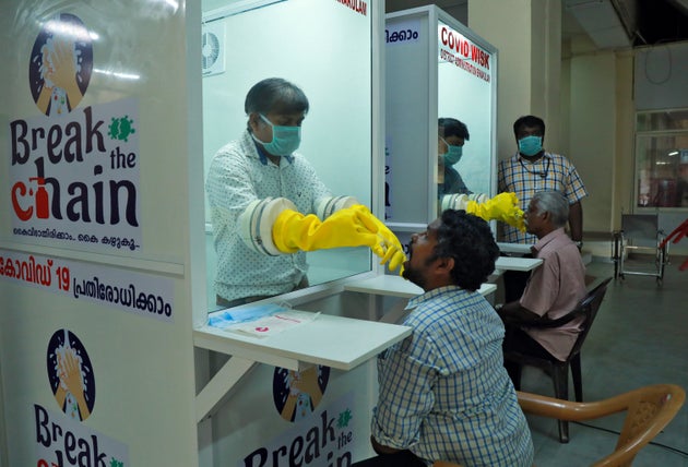 Medical staff members of a government-run medical college collect swabs from people to test for coronavirus...