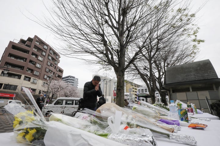 「志村けんの木」横の献花台に花を手向け、手を合わせる男性＝3月30日、東京都東村山市