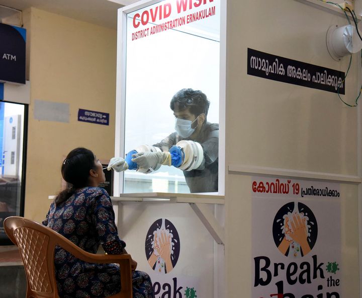 A medical staff collects samples from a woman at a new walk-in coronavirus testing kiosk at Ernakulam Medical Collage at Kochi in Kerala, on April 11, 2020. 