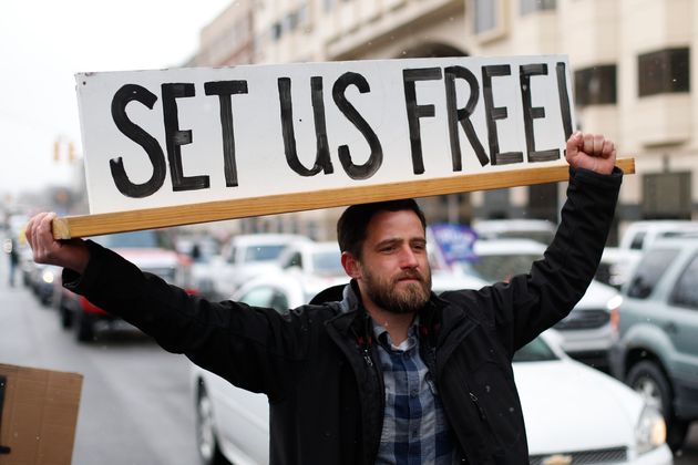 Steve Polet holds a sign during a protest at the State Capitol in Michigan last week  