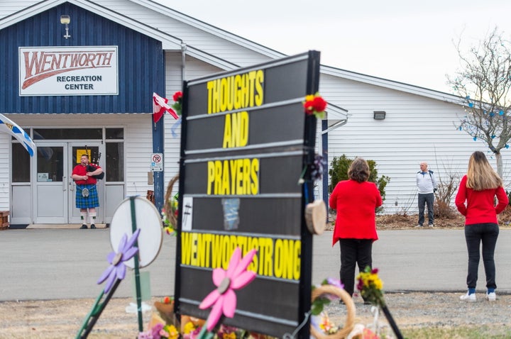 A piper plays "Amazing Grace" as residents look on during a local vigil in Wentworth, N.S. on Friday.