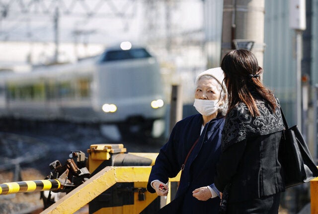 JR宝塚線脱線事故から15年。事故発生時間帯に現場マンション近くの踏切に立つ遺族の藤崎光子さん（右から2人目）=25日午前9時18分、兵庫県尼崎市、代表撮影