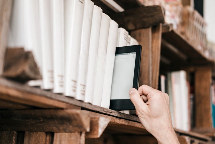 Hand taking e-book from book shelf