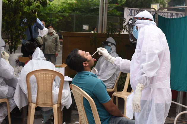 A medical worker in a PPE suit takes a swab sample while conducting a COVID-19 test for media persons,...