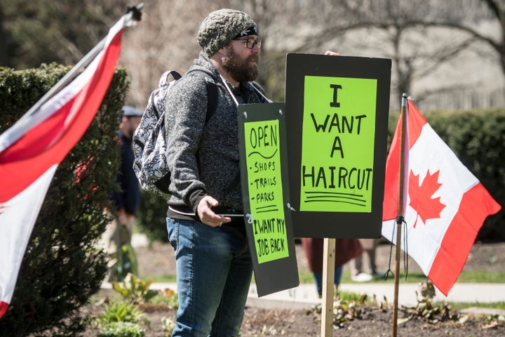 A demonstrator holds a sign during a protest to end the shutdown due to COVID-19 at Queen's Park in Toronto on Saturday.