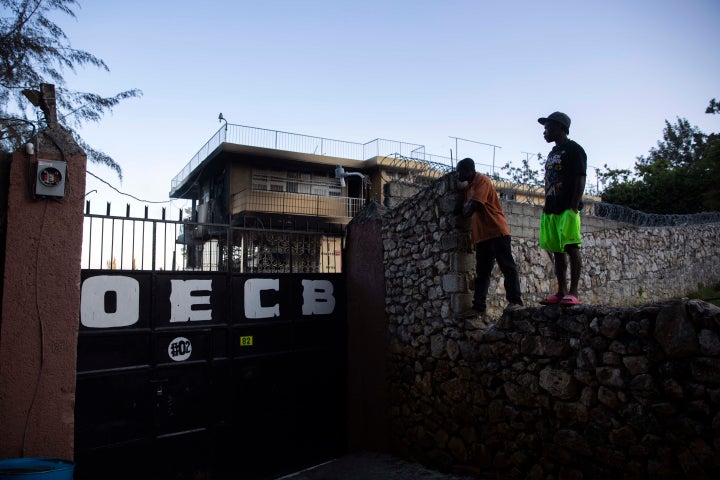 In this March 14, 2020 file photo, residents stand on top of a wall to see inside the property of a children's home run by th