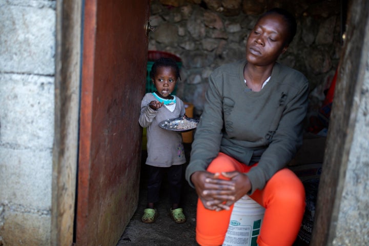 Two-year-old Badinal St. Juste eats rice behind her mother Tania Caristan at their home in Kenscoff, on the outskirts of Port