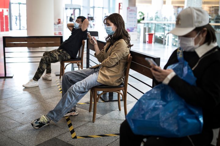 Customers sit in chairs waiting for Starbucks coffee in Shopping Mall on April 25, 2020 in Wuhan, China.