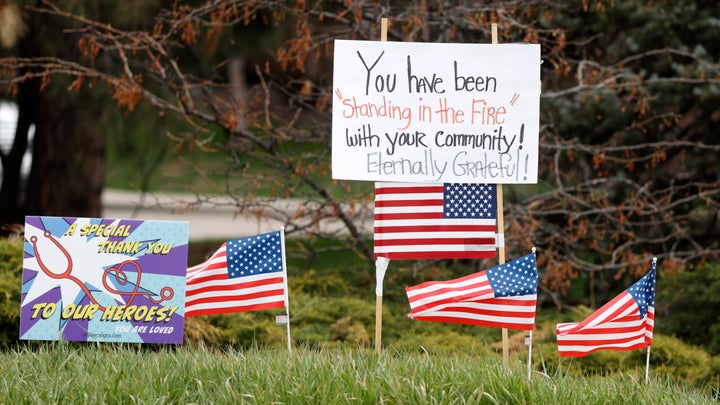 Signs and U.S. flags stand in honor of healthcare workers, across from Littleton Adventist Hospital on Sunday, April 26, 2020