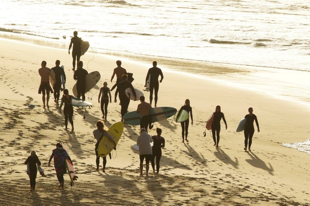 Surfers walk as Bondi Beach reopens to surfers and swimmers after it was closed to curb the spread of the coronavirus disease (COVID-19), with strict social distancing measures remaining in place, in Sydney, Australia, April 28, 2020. REUTERS/Loren Elliott