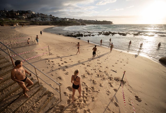 SYDNEY, AUSTRALIA - APRIL 28: The first swimmers run into the water as Bronte Beach is reopened at Bronte Beach on April 28, 2020 in Sydney, Australia. Waverley Council reopened Bondi, Bronte and Tamarama beaches today, with COVID-19 social distancing rules still in place. The beaches will be open from 7am to 5pm for swimmers and surfers on weekdays, but will remain closed on weekends. Several beaches in Sydney's Eastern suburbs were closed March 28, after large crowds were seen gathering at Bondi Beach despite social distancing orders in place to slow the spread of COVID-19. (Photo by Ryan Pierse/Getty Images)