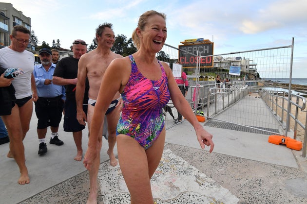 Beachgoers smile as they arrive for their first swim after Bondi Beach reopened following a five week closure in Sydney on April 28, 2020, amid the novel coronavirus pandemic. - Swimmers and surfers returned to Sydney's famed Bondi Beach almost six weeks after it was closed amid a spike in coronavirus cases. (Photo by Saeed KHAN / AFP) (Photo by SAEED KHAN/AFP via Getty Images)