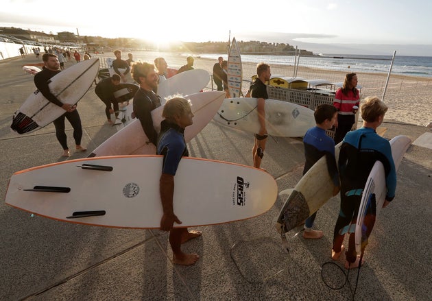 Surfers wait for officials to open Bondi Beach in Sydney, Tuesday, April 28, 2020, as coranavirus pandemic restrictions are eased. The beach is open to swimmers and surfers to exercise only. (AP Photo/Rick Rycroft)