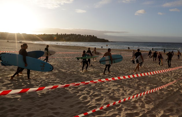 Surfers prepare to enter the water at Bondi Beach in Sydney, Tuesday, April 28, 2020, as coronavirus pandemic restrictions are eased. The beach is open to swimmers and surfers to exercise only. (AP Photo/Rick Rycroft)