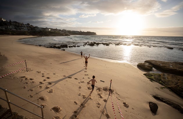 SYDNEY, AUSTRALIA - APRIL 28: The first swimmers run into the water as Bronte Beach is reopened at Bronte Beach on April 28, 2020 in Sydney, Australia. Waverley Council reopened Bondi, Bronte and Tamarama beaches today, with COVID-19 social distancing rules still in place. The beaches will be open from 7am to 5pm for swimmers and surfers on weekdays, but will remain closed on weekends. Several beaches in Sydney's Eastern suburbs were closed March 28, after large crowds were seen gathering at Bondi Beach despite social distancing orders in place to slow the spread of COVID-19. (Photo by Ryan Pierse/Getty Images)