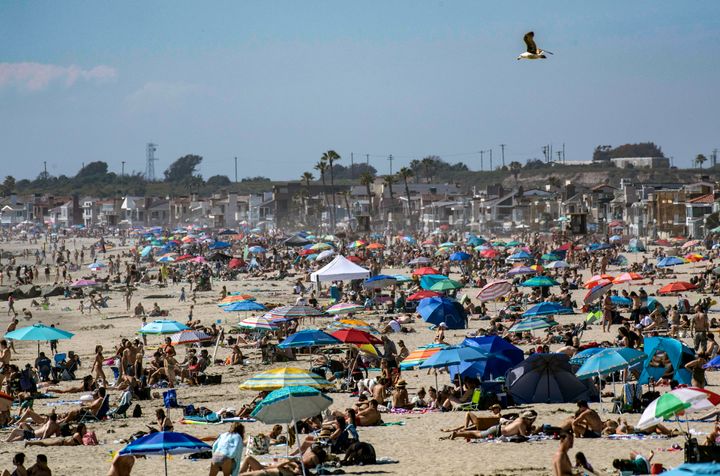 Large crowds gather near the Newport Beach Pier in California on Saturday, April 25, to cool off during the hot weather despite the coronavirus pandemic.