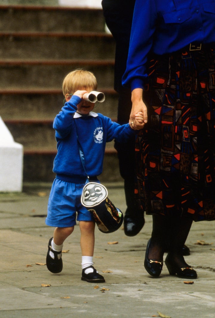 Prince Harry looks at photographers with a pair of binoculars as he leaves on his first day at Mrs. Mynor's nursery school on