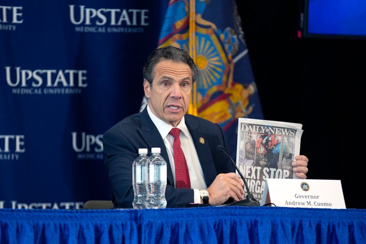 New York Gov. Andrew Cuomo holding up an article about problems with homeless people riding the subway.