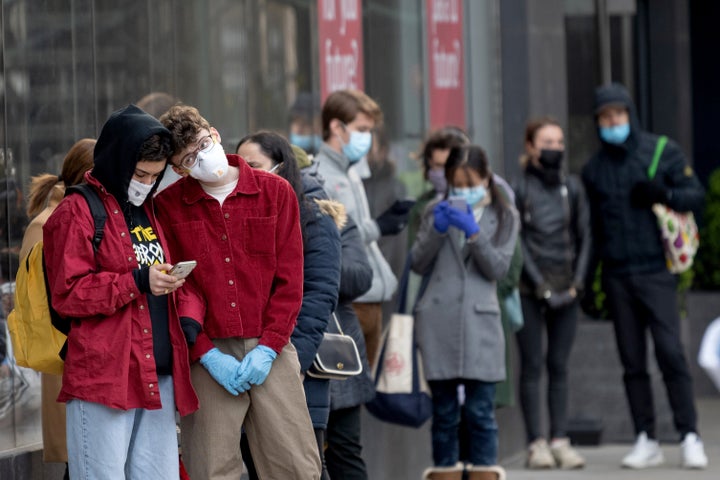 People wearing protective masks stand in line for a supermarket in New York City on April 16. 