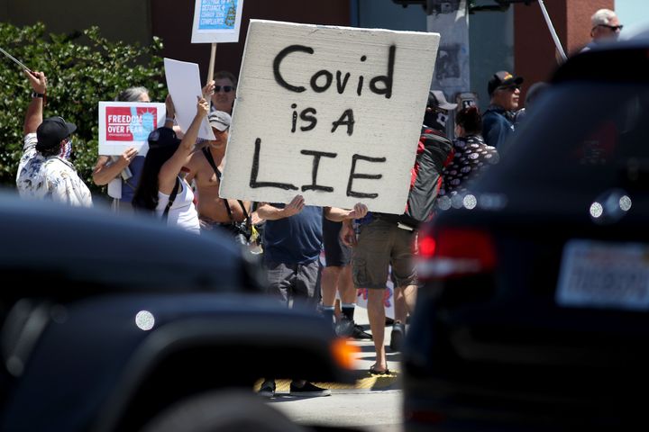 Protesters hold banners and chant against state government measures intended to curb the spread of COVID-19 during an Open California rally on April 26, 2020, in San Diego.