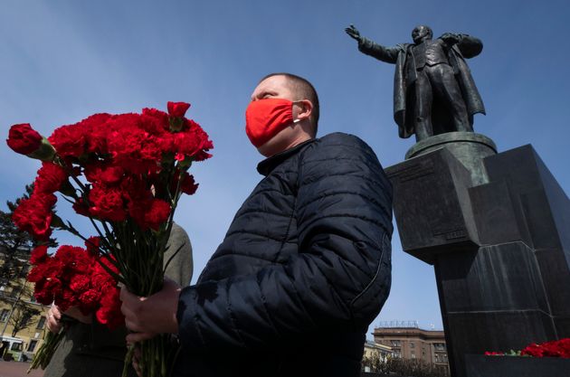 Με κόκκινη μάσκα παραμονή της Εργατικής Πρωτομαγιάς ένα μέλος του Κομμουνιστικού Κόμματος της Ρωσίας. Εδώ μπροστά το άγαλμα του Βλάντιμιρ Λένιν (Αγία Πετρούπολη)
