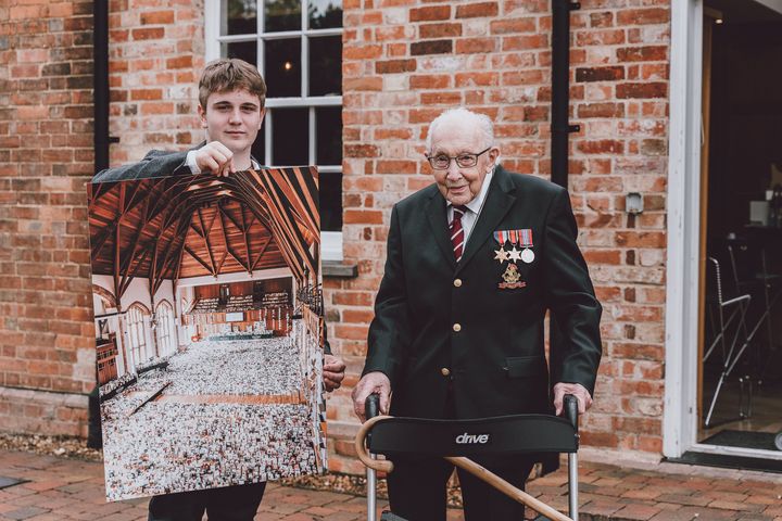 Benjie Ingram-Moore presenting his grandfather Captain Tom Moore with a photograph of the Great Hall of Bedford School, Bedfordshire, filled with cards for his 100th birthday.