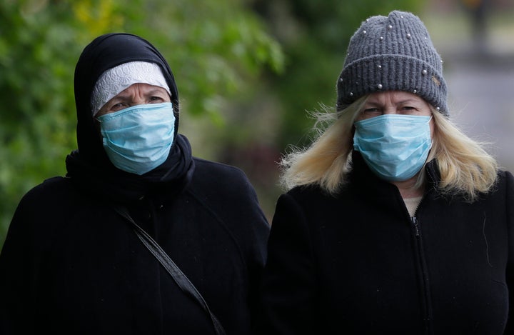 People wear face masks to protect against the coronavirus as they walk in London.