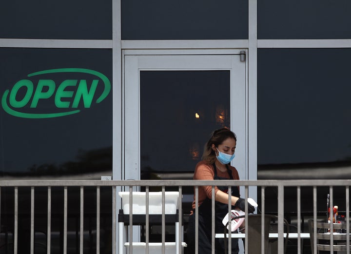 A restaurant employee cleans a outdoor patio table at Benny's Cafe prior to the Texas' scheduled reopening of businesses during the coronavirus pandemic on April 27, in Colleyville, Texas.