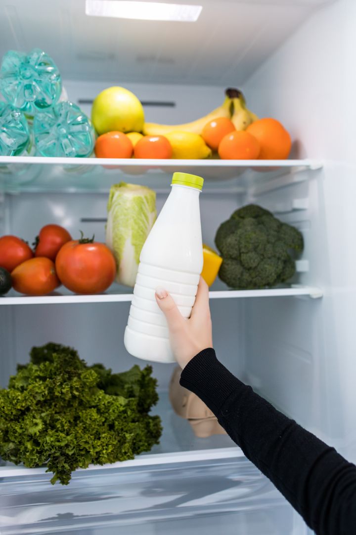 Woman standing in front of fridge and taking milk.