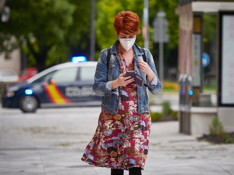 A woman wearing a mask looks at her phone on April 30 in Pamplona, Spain. The Spanish government has unveiled its plan for ea