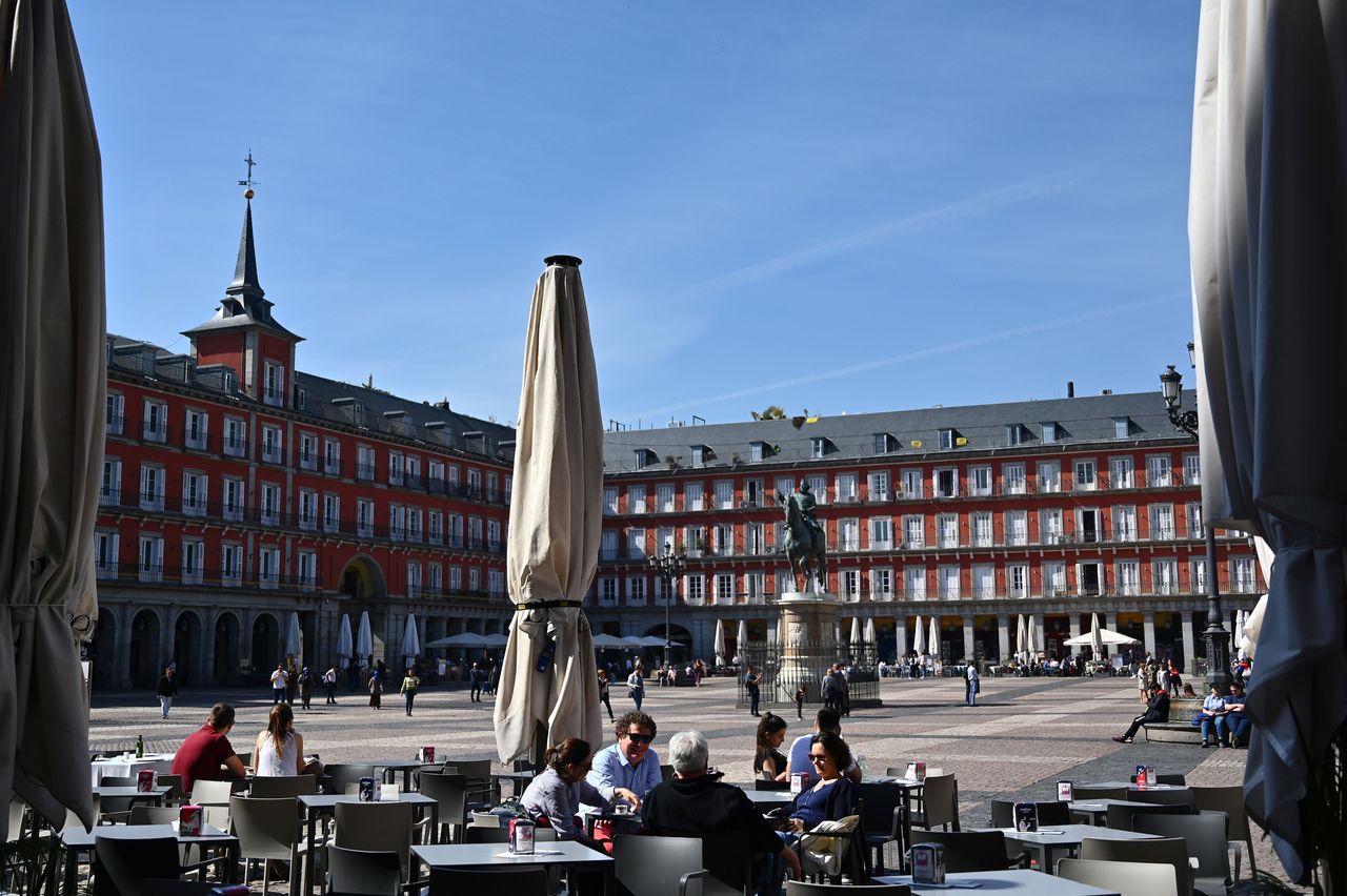 People sit at a terrace at Madrid's Plaza Mayor on March 13 as the city's mayor announced that he would order the closure of all outdoor bar and restaurant terraces. Under Spain's plan to ease lockdown restrictions, sidewalk cafes will be allowed to reopen with limited capacity.