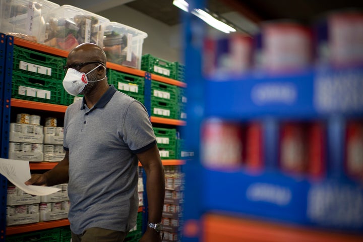 First Love foundation food bank co-founder, Aerold Bentley walks past goods for distribution to families, at the First Love foundation foodbank warehouse in Tower Hamlets.