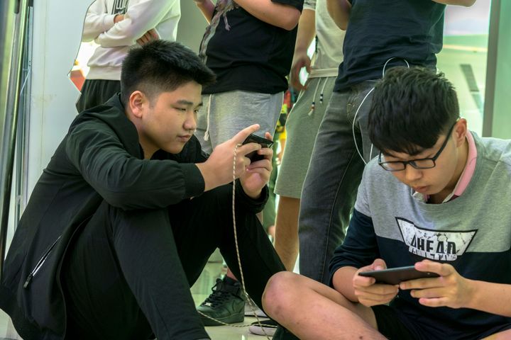 スマホゲームで対戦する中国の若者