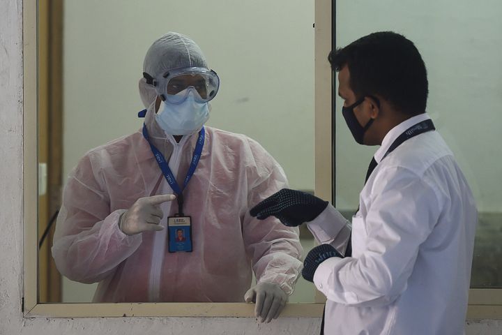 A man wearing a protective suit stands in a waiting room used for people to be tested for the COVID-19 in Mumbai.