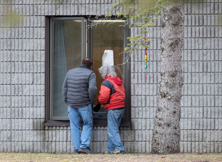 Visitors visit residents through a window at Pinecrest Nursing Home on March 30 in Bobcaygeon, Ont.