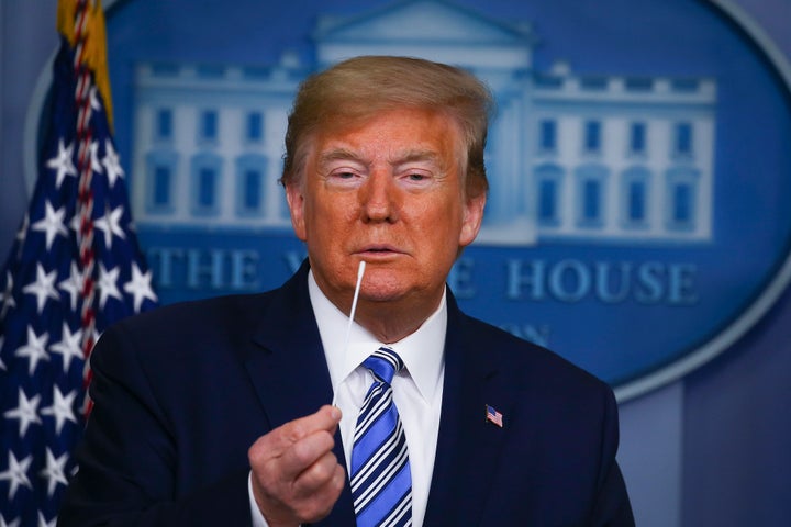 President Donald Trump holds up swabs as he speaks at the daily coronavirus briefing at the White House on April 19.