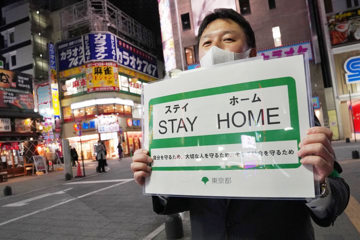 「STAY HOME」を呼びかける都職員。繁華街も人影はまばらだ＝4月10日、東京都新宿区